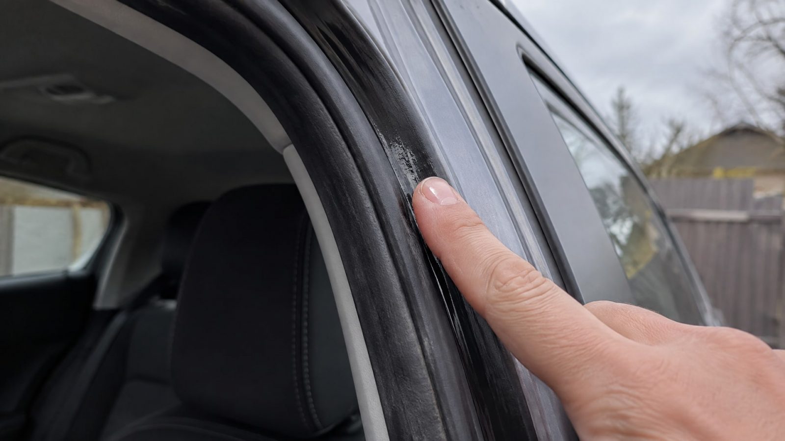 Палец наносит прозрачную силиконовую смазку на уплотнитель автомобильной двери.